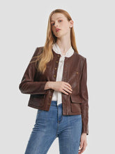A woman wears a brown leather jacket and blue jeans.